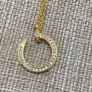 Cartier's Classic Gold Nail Pendant Necklace With Diamonds Set Around The Edge.